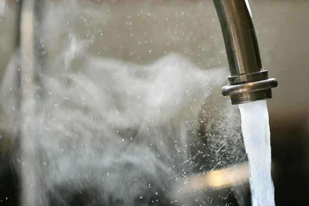 Hot water coming out of a faucet with steam rising up.