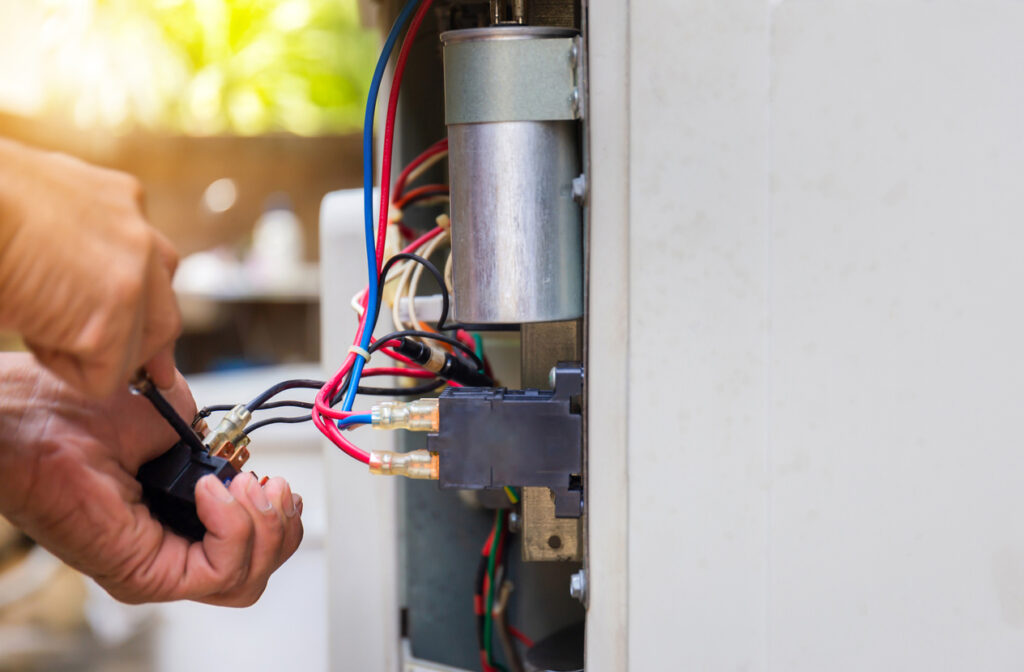 Pair of hands repairing an air conditioner, changing magnetic contactor
