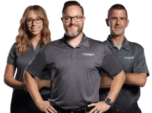 Three Donnelly's team members wearing gray polos and standing together, smiling, on white background.