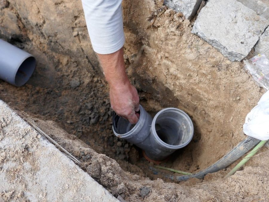 Plumber inspecting pipes underneath sewer line